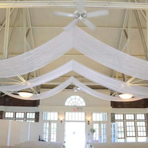 Three rows of white sheer fabric with multiple swoops hanging over the length of the main room at The Prospect Park Picnic House.
