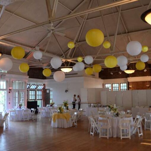 Yellow and White Paper Lanterns hanging with LED Lights inside hanging inside The Prospect Park Picnic House. Also, amber wireless Up-Lights are around the inside perimeter of The Prospect Park Picnic House.