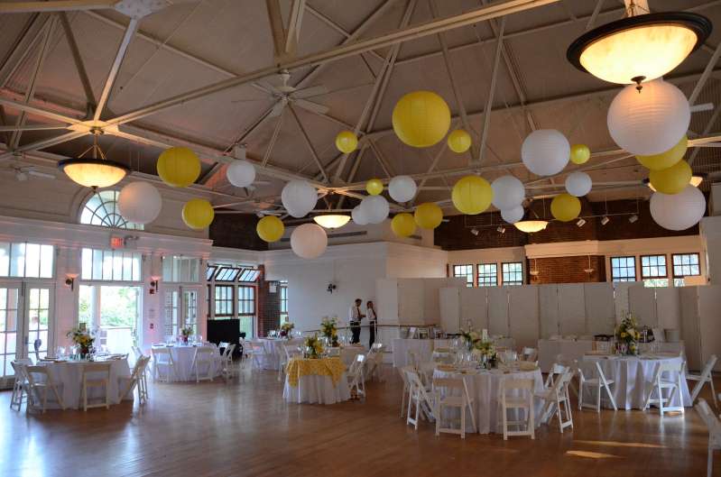 Yellow and White Paper Lanterns hanging with LED Lights inside hanging inside The Prospect Park Picnic House. Also, amber wireless Up-Lights are around the inside perimeter of The Prospect Park Picnic House.