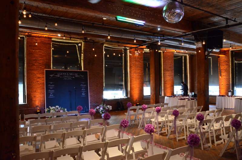 Warm White String Lights hanging between the center columns for a wedding at The Dumbo Loft.  Also, Up-Lights around the perimeter of the main room.