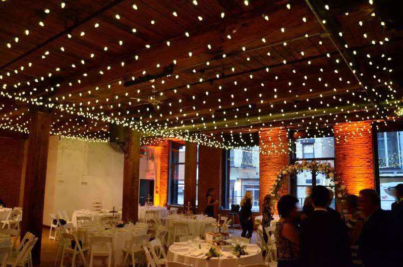 Mini-LED string lights hanging in multiple parallel lines as a canopy at The Dumbo Loft. Also, up-lights setup around the perimeter walls.