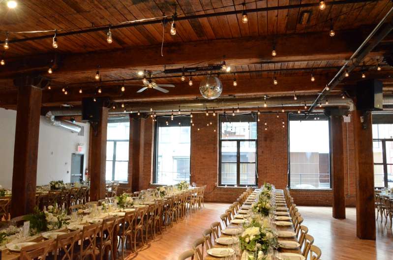 String Lights with S14 bulbs hanging in a zigzag pattern between the center columns for a wedding at The Dumbo Loft.