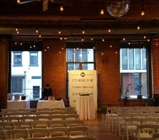 String Lights with S14 bulbs hanging in a zigzagging pattern between the columns at The Dumbo Loft.  Provided amber Up-Lights around the perimeter of the room.
