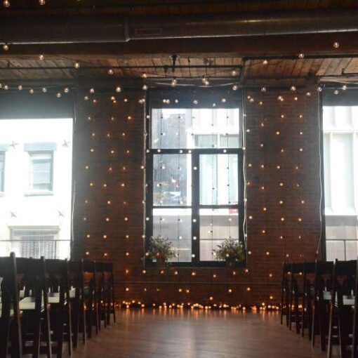 String Lights overhead between the center columns at The Dumbo Loft. Also, String Lights hanging vertically as a backdrop behind the ceremony area at The Dumbo Loft.