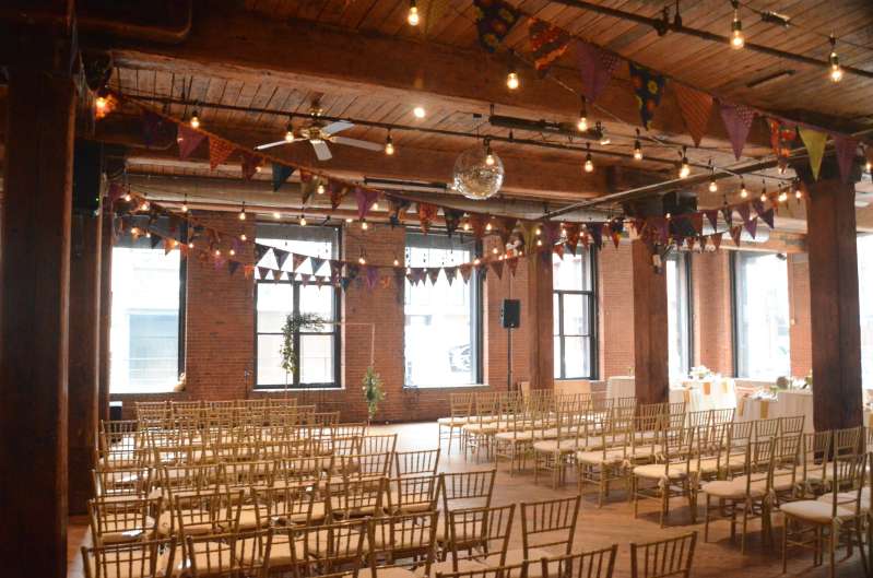 String Lights hanging between center columns for a wedding at The Dumbo Loft with pennant flags.