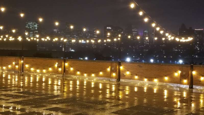 String Lights are hanging above and along the wall of the outdoor terrace at The Bordone in Long Island City.