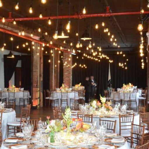 Pendant Lamps hanging between the center columns above the full length of The Harbor Room at The Liberty Warehouse. Also, Up-Lights around the perimeter wall. In addition, Up-Lights at the base of each center column.