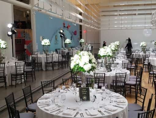 Pin-spot on The Bar and The Table Centerpieces for a wedding at The Queens Museum. Also, a warm white wash  on rectangular glass installation hanging above the dinner tables at The Queens Museum. In addition, a custom gobo projection on wall at The Queens Museum.