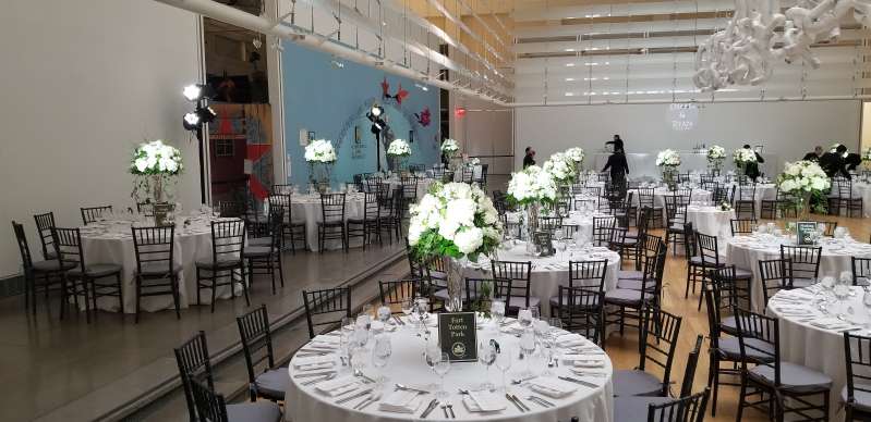Pin-spot on The Bar and The Table Centerpieces for a wedding at The Queens Museum. Also, a warm white wash  on rectangular glass installation hanging above the dinner tables at The Queens Museum. In addition, a custom gobo projection on wall at The Queens Museum.