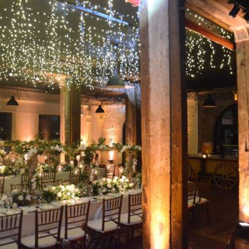 Icicle (Fairy) Lights hanging the length of the 1st floor reception at The Liberty Warehouse.  Also, Up-Lights along the perimeter wall and at the base of each column.  In addition, Pin-Spot highlighting floral centerpiece on each table.