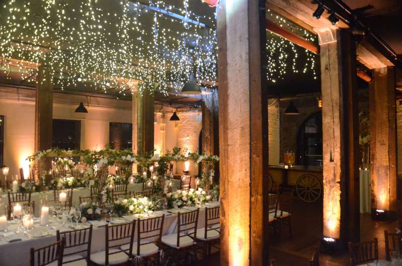 Icicle (Fairy) Lights hanging the length of the 1st floor reception at The Liberty Warehouse.  Also, Up-Lights along the perimeter wall and at the base of each column.  In addition, Pin-Spot highlighting floral centerpiece on each table.