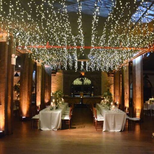 Icicle (Fairy) Lights hanging the length of the 1st floor reception at The Liberty Warehouse.  Also, Up-Lights along the perimeter wall and at the base of each column.  In addition, Pin-Spot highlighting floral centerpiece on each table.