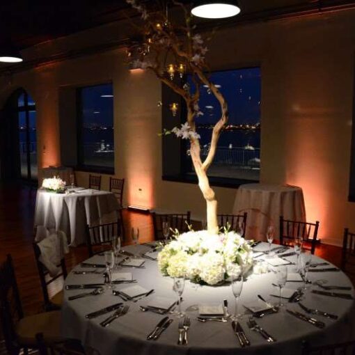 Pin-Spots hanging overhead and highlighting the centerpiece at each table. Also, Up-Lights around the perimeter of the reception room at The Liberty Warehouse. 