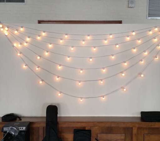 String Lights hanging horizontally with multiple swooping cords against wall behind the entertainment on the first floor at The Liberty Warehouse.