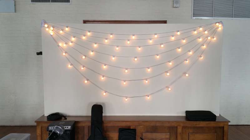 String Lights hanging horizontally with multiple swooping cords against wall behind the entertainment on the first floor at The Liberty Warehouse.