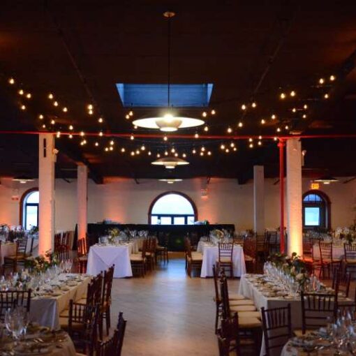 String Lights (Bistro/Cafe Lights) hanging above the dance floor at The Liberty Warehouse. Also, Up-Lights around the perimeter of the room and at the base of each column. 