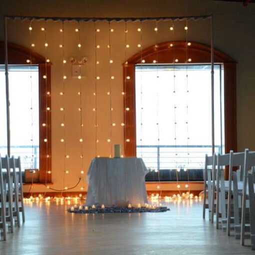 A curtain of string lights hanging vertical behind the Ceremony area in The Governor's Room at the Liberty Warehouse.