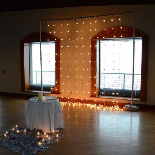 A curtain of string lights hanging vertical behind the Ceremony area in The Governor's Room at the Liberty Warehouse.