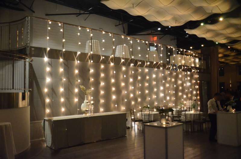Vertical String Lights hanging against a wall for a wedding at Current at Pier 59 inside Chelsea Piers in NYC.