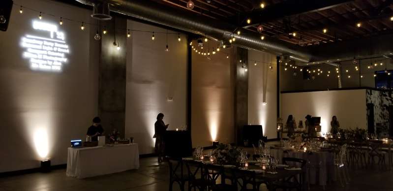 String Lights hanging overhead along with Up-Lights against the perimeter walls or an open house at Dobbin St. Also, a custom gobo projector displaying an image on wall at Dobbin St..