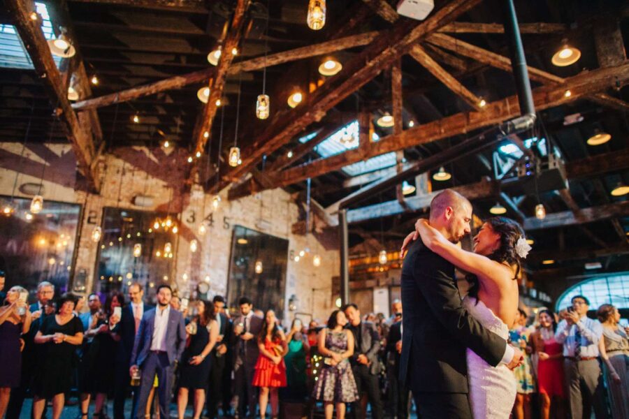 A combination of string lights and pendant lamps with mason jars hanging over the dance floor at The Houston Hall.