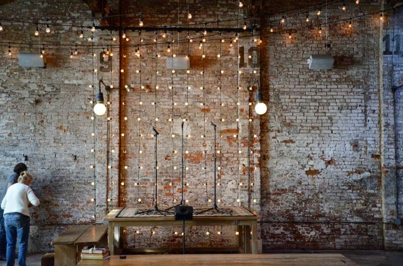String lights hanging vertically against the wall to create a curtain of lights the band and ceremony.
