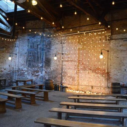 Vertical String Lights hanging against the wall as a backdrop behind the ceremony area for a wedding at The Houston Hall.