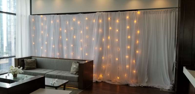 Vertical String Lights w/ white sheer and non-sheer drapes hanging against a wall at The RoofTop at Exchange Place.