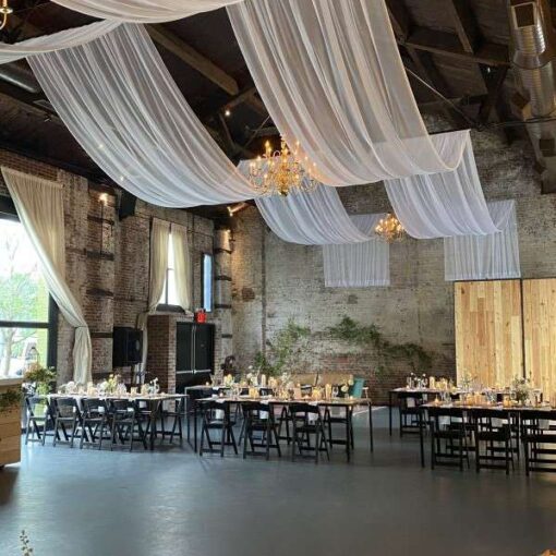 White Sheer drapes hanging in two parallel lines over The Main Room for a wedding at The Green Building.
