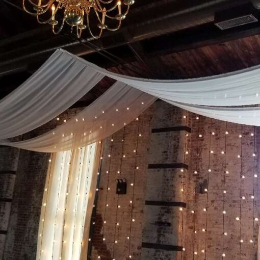 A pair of white sheer drapes hanging above ceremony area for a wedding at The Green Building.
