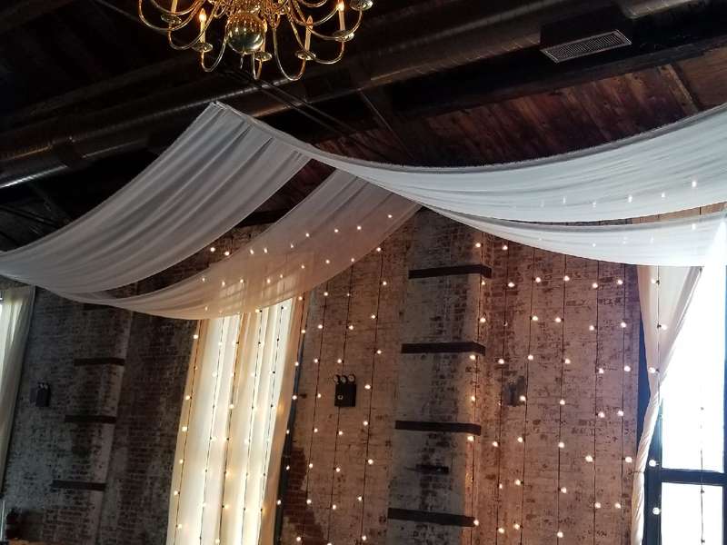 A pair of white sheer drapes hanging above ceremony area for a wedding at The Green Building.