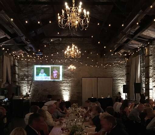 String Lights hanging over the majority of the main room for a wedding at The Green Building. Also Warm White Up-Lights are setup along the perimeter wall of The Green Building.