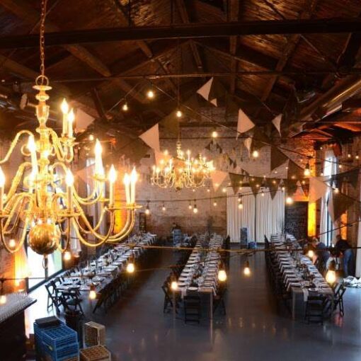 String lighting with bunting flags for a Black-Tie Halloween Masquerade Wedding at The Green Building in Brooklyn, NY. Also, amber up-lights around the perimeter of walls. In addition, two moving head LED lighting fixtures and Two PAR 64 LED effects lights over dance floor.