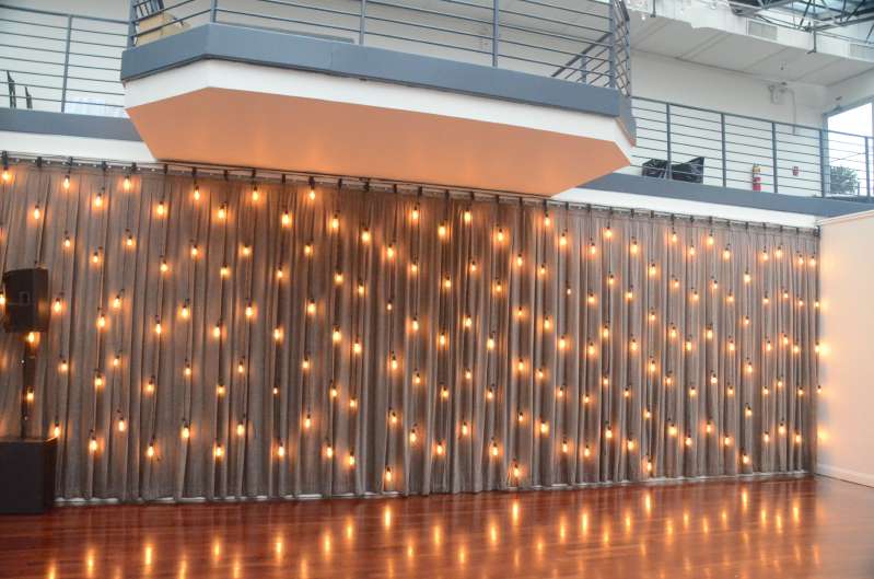 A vertical curtain of string lights hanging as a backdrop against rear dance floor wall at The Tribeca Rooftop.