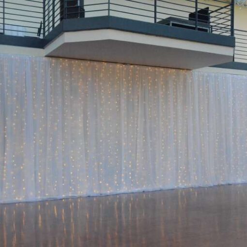 White Sheer and Non-Sheer curtains with LED String Lights hanging vertically as backdrop against the dancefloor at The Tribeca Rooftop.