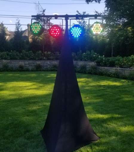 A Sound Activated and Color Changing LED wash hanging from a tripod lighting stand setup outdoors next to the dance floor.