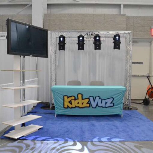 A "Goal Post Shape" truss structure with moving intelligent Lights and a Flat Screen TV for a booth at the Play Fair event at The Jacob K. Javits Convention Center in NYC.