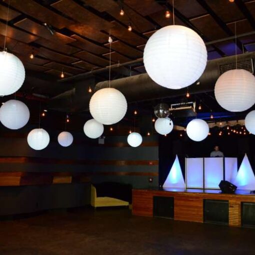 A dreamy wedding reception with string lights and elegant white paper lanterns at Littlefield in Brooklyn, NY.