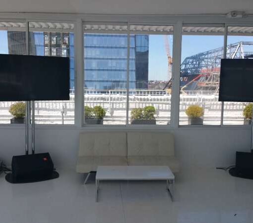 Two 60" Flat Screen TV suspended on a 6ft stand along with a wireless microphone and speakers for The Annual Wines Of Jura Grand Tasting in New York hosted at Studio 450.