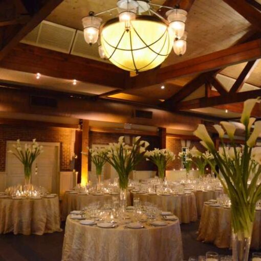 Amber Up-Lights is along the reception room walls for a wedding at The Central Park Boat House in New York City.