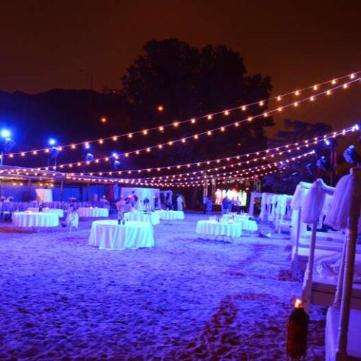 String Lights (Cafe Lights/ Bistro Lights) hanging outdoors above the beach area for a wedding at La Marina in Washington Heights.