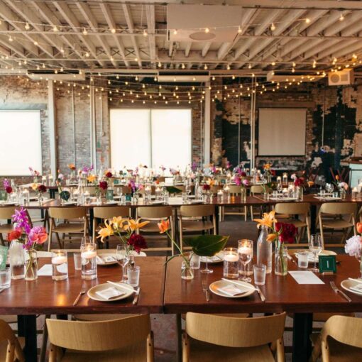 A long dinner table with florals set in The Corner Room at Rule of Thirds with warm white String Lights hanging overhead.
