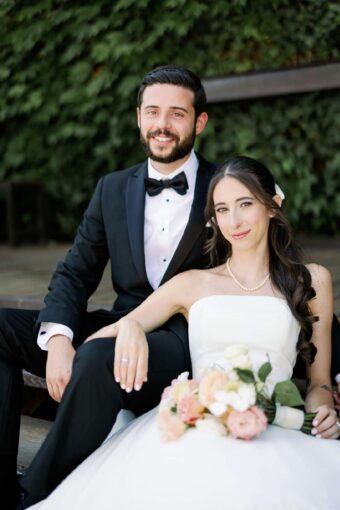 Gianna + Steven sitting on The Porch in the courtyard for their summer wedding at The Foundry