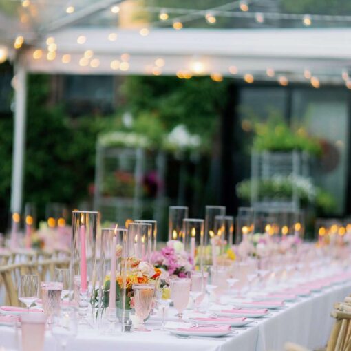The table setting for a summer wedding reception under a clear top tent with String Lights hanging overhead in the courtyard at The Foundry