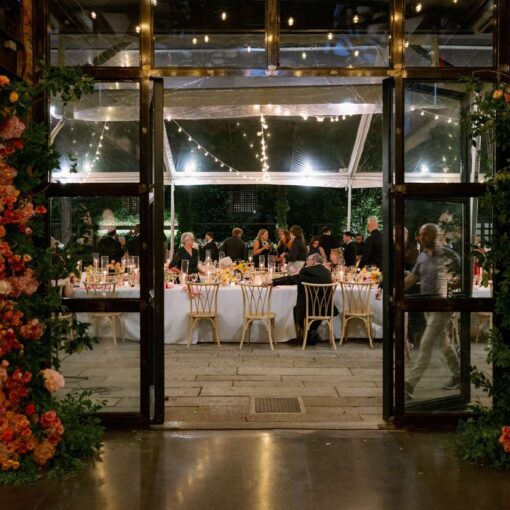 A summer wedding reception under a clear top tent with String Lights hanging overhead in the courtyard at The Foundry