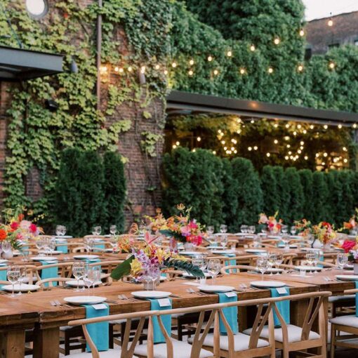 Dinner tables in the courtyard for Tina & Real's outdoor NYC wedding reception at The Foundry with String Lights hanging overhead.