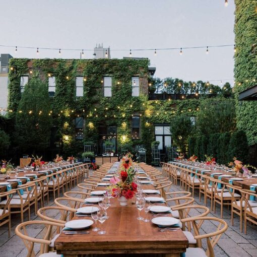 Dinner tables in the courtyard for Tina & Real's outdoor NYC wedding reception at The Foundry with String Lights hanging overhead.