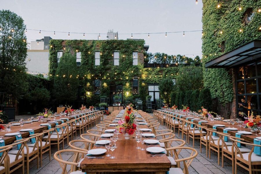 Dinner tables in the courtyard for Tina & Real's outdoor NYC wedding reception at The Foundry with String Lights hanging overhead.