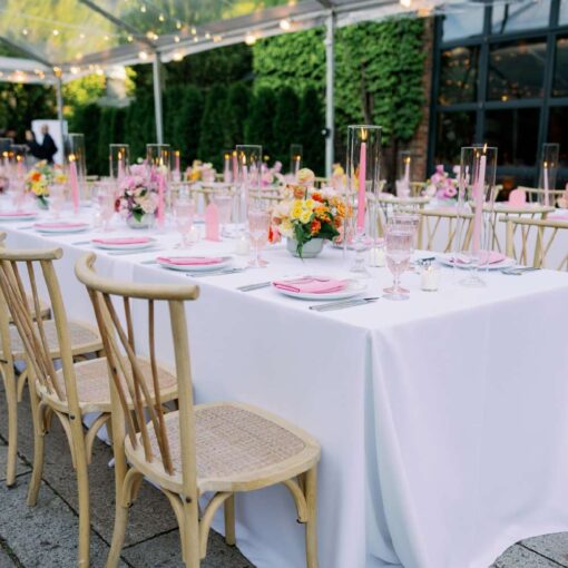 The table setting for a summer wedding reception under a clear top tent with String Lights hanging overhead in the courtyard at The Foundry