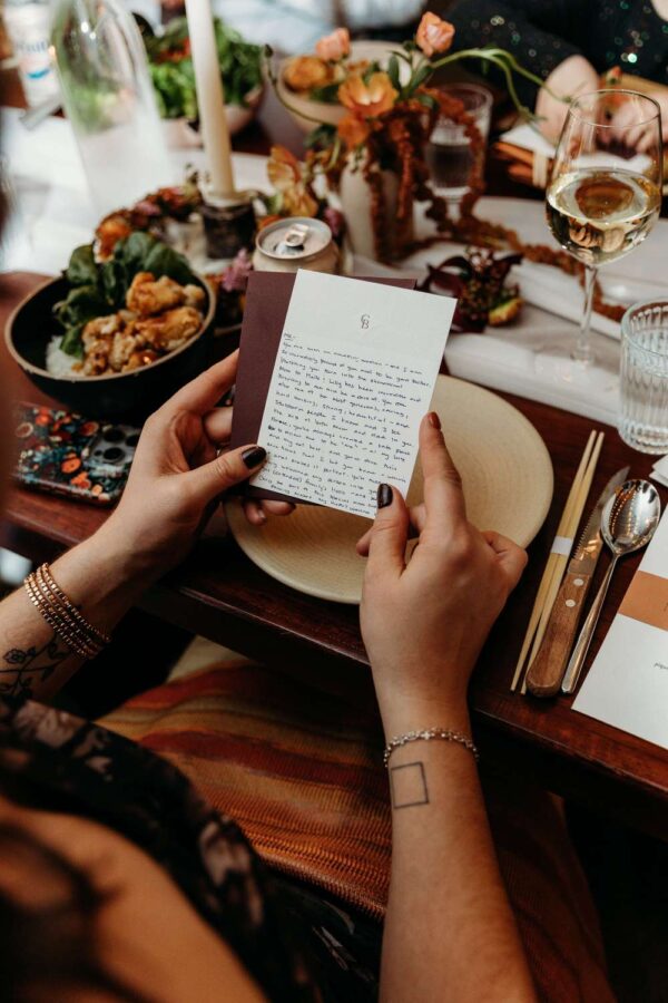 A wedding guest holding a card with a note, amidst a beautifully set table at Rule of Thirds.